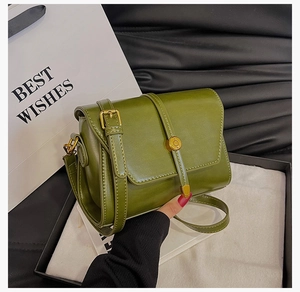 Détail d'un petit sac carré en cuir PU vert foncé avec fermoir doré dans son coffret