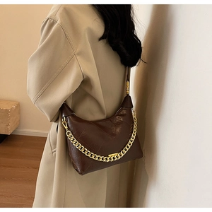 Detail of dark brown leather hobo bag featuring large quilted pattern and gold chain