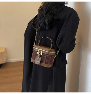 Detail view of a vintage plaid bucket bag with gold chain strap on a black blazer