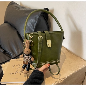Détail du sac seau vert foncé avec fermoir doré et charm de lapin mignon