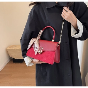 Detail of red leather crossbody bag with suede stitching and heart pattern silk scarf