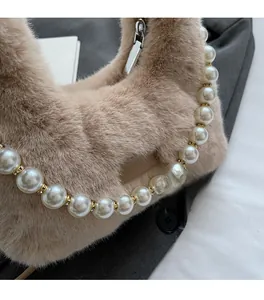 Dettaglio borsa di peluche beige con manico di perle finte e dettagli in metallo dorato