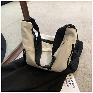 Detail of white nylon hobo bag featuring black buckle and woven cord zipper pull