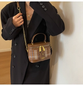 Brown vintage checkered box bag with chain strap shown on black coat for fashion details