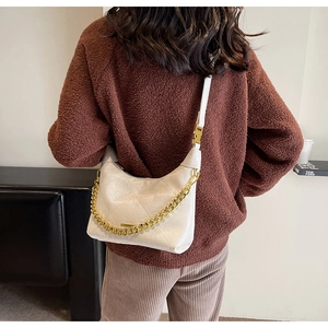 Detail of white quilted crescent bag with gold chain and leather shoulder strap on model