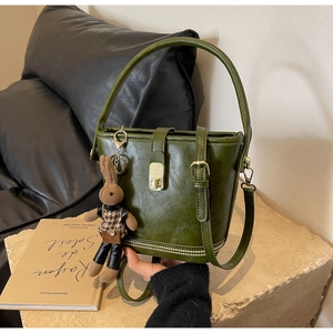 Détail du sac seau vintage en cuir vert avec fermoir doré et pendentif lapin brodé