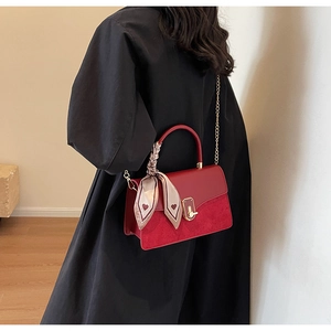 Detail of red PU leather handbag with gold twist lock and heart print scarf