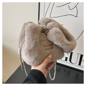 Close-up of plush faux fur bucket bag with metal tag and elegant silver chain strap