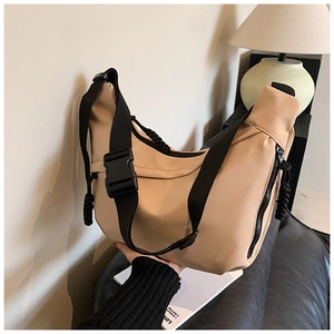 Detailed view of beige nylon crossbody crescent bag with black strap and buckle