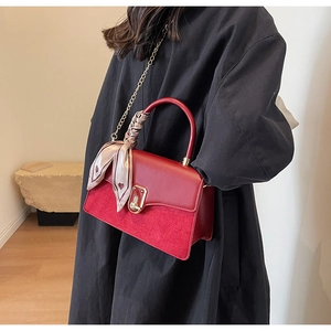 Detail of red paneled handbag with metal lock, chain strap and heart print silk scarf