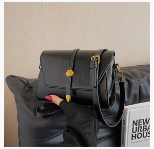 Gros plan d'un petit sac carré noir rétro avec texture mate et boucle dorée