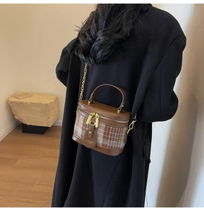 Detail of brown faux leather and blue plaid bucket bag with gold chain strap