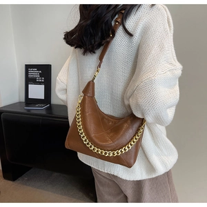 Detail of dark brown quilted leather dumpling bag with chunky gold chain strap