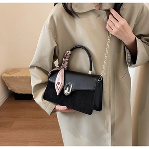 Detail of black leather and suede bag with gold clasp, pink silk scarf on handle