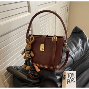 Détail du sac seau en cuir marron foncé avec fermoir doré et pendentif lapin en peluche