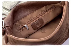 Detailed view of the brown leather bag interior featuring a zip pocket and soft fabric lining