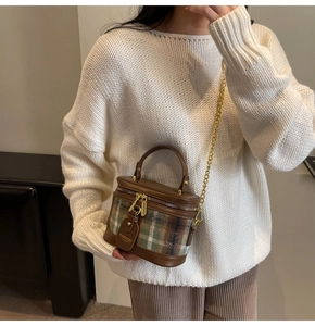 Detail of vintage brown leather and green plaid cylinder bucket bag with chain strap