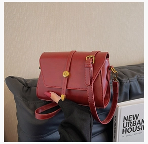 Gros plan d'un sac à bandoulière en cuir PU rouge foncé avec boucle dorée