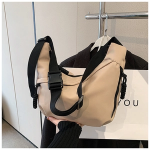 Detail of adjustable black strap and buckle on the beige nylon crescent crossbody bag