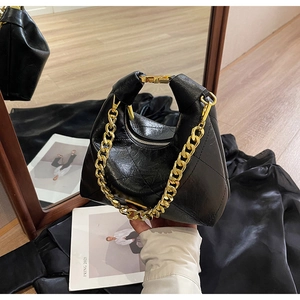 Detail of black quilted dumpling bag with vintage gold chain handle and metal buckle