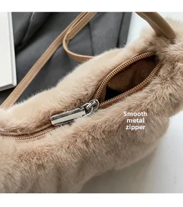 Dettaglio della cerniera in argento su borsa a mano in peluche beige con chiusura