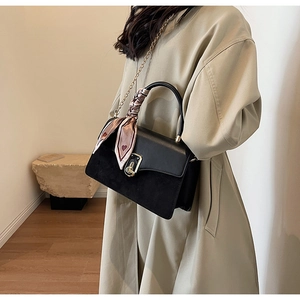 Detail of black PU leather crossbody bag with silk scarf handle and gold chain strap