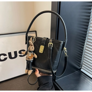 Détail du sac seau noir en cuir PU avec boucle dorée et breloque lapin en peluche