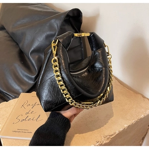 Detail of black glossy croissant bag with gold chunky chain and pleated texture