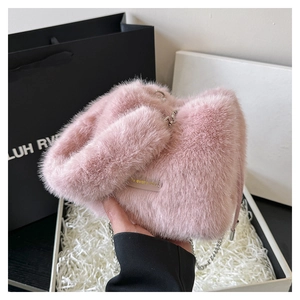 Detail of soft pink plush bucket bag featuring a gold plate and silver chain strap