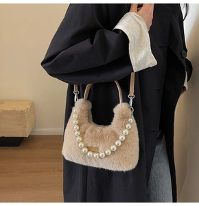 Dettaglio borsa di peluche beige con manico in perle e placchetta metallica del marchio