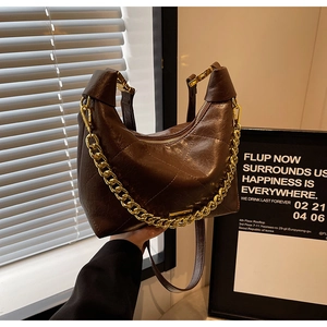 Detail of retro brown quilted hobo bag with glossy finish and gold chunky chain strap