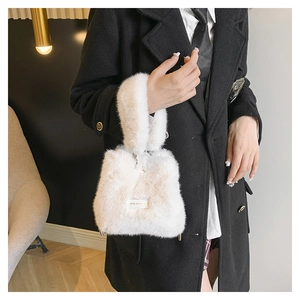 Detail of soft white faux fur bucket bag with plush handle and embroidered patch
