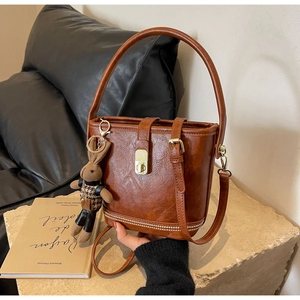 Détail du sac seau marron vintage avec fermoir doré, strass et breloque lapin en peluche
