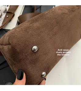 Dettaglio del fondo borsa in pelle scamosciata marrone con rivetti protettivi in argento