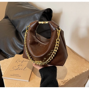 Detail of vintage brown leather handbag with gold chain and quilted texture