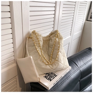Détail du sac seau matelassé beige avec chaîne et sa petite pochette zippée assortie