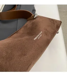 Dettaglio della borsa a tracolla in pelle scamosciata marrone con scritte bianche
