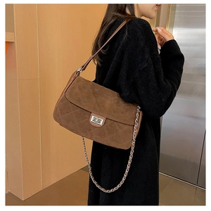 Macro detail of brown quilted suede shoulder bag featuring a silver square twist lock
