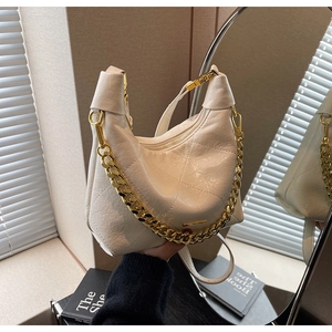 Close-up of cream quilted hobo bag with gold chain and textured leather details