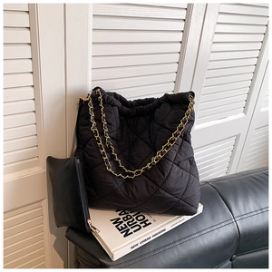 Détail d'un sac seau matelassé noir avec bandoulière chaîne et pochette assortie