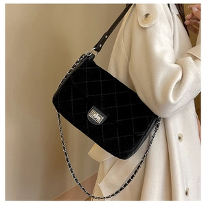 Detail of black quilted chain bag with silver twist lock on a white wool coat