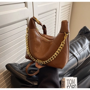 Close-up of retro brown quilted leather crescent bag with chunky gold chain strap