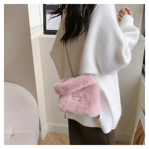 Detail of pink plush bucket bag with silver chain strap on a model wearing a white sweater