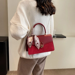 Red PU leather crossbody bag with silk scarf and gold chain strap on white sweater