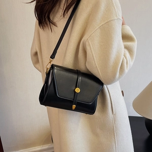 Sac bandoulière carré en cuir PU noir avec boucle dorée porté par un mannequin