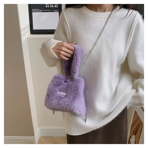Detail of purple faux fur bucket bag with silver chain strap on a white knit sweater
