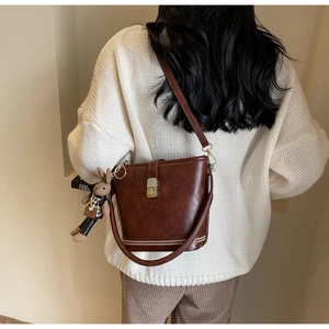 Détail du sac seau marron en similicuir avec fermoir doré et charm lapin sur mannequin