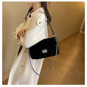 Close-up of black quilted shoulder bag featuring silver twist lock and chain strap