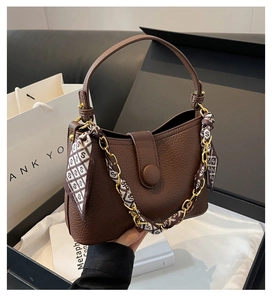 Detail of dark brown lychee grain leather handbag with silk scarf chain handle in a gift box