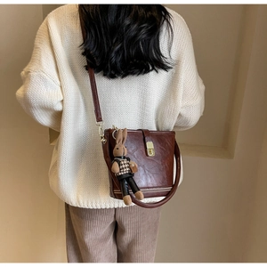 Détail du sac seau marron foncé avec un charmant lapin en peluche et un fermoir doré chic